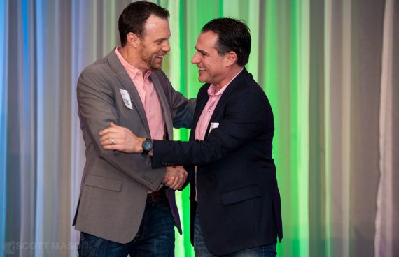 two men hugging on stage at a corporate event