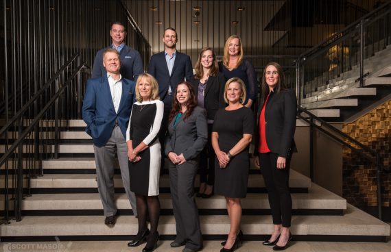 a group of employees posing on the stairs of an Austin hotel for a corporate group portrait