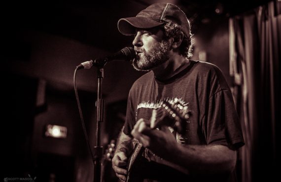 a sepia photo of Austin musician Scott H Biram performing live