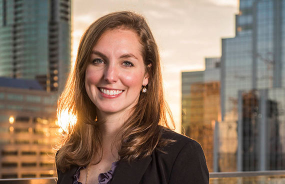 a business portrait/headshot of a smiling woman standing on a rooftop downtown