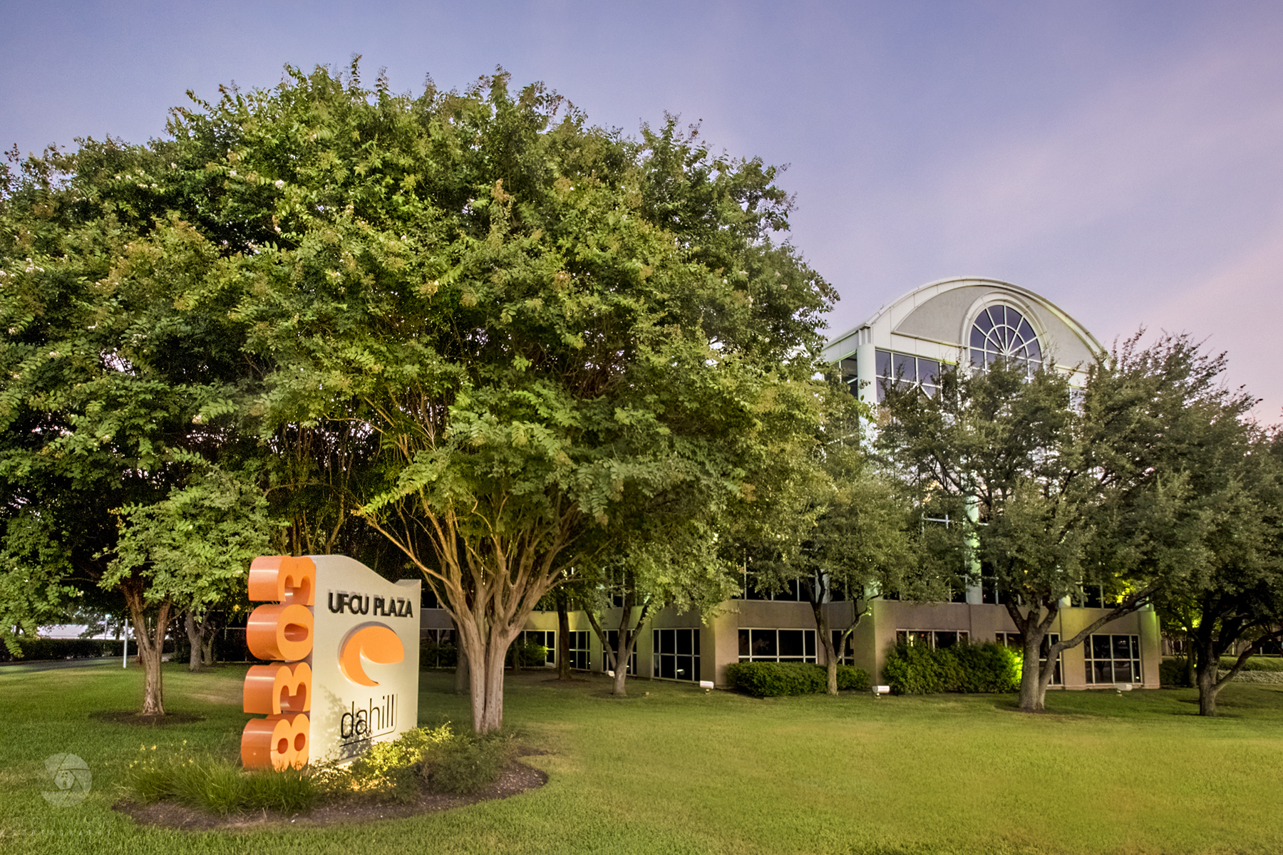 An exterior image of UFCU plaza in Austin with a monument sign and tree