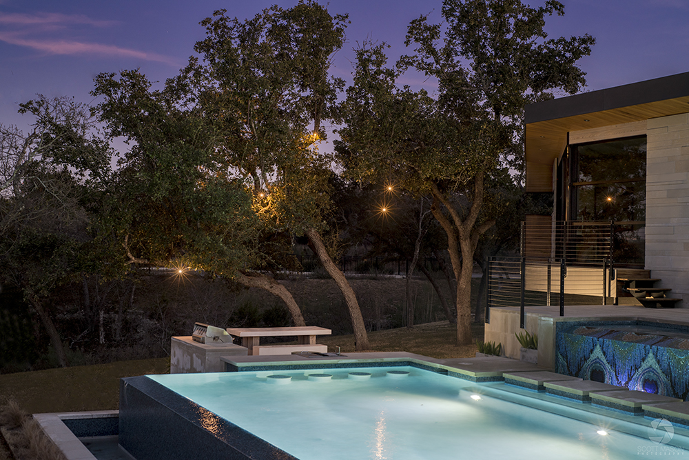 A twilight architectural photo of a pool and outdoor tree lighting in Austin, TX