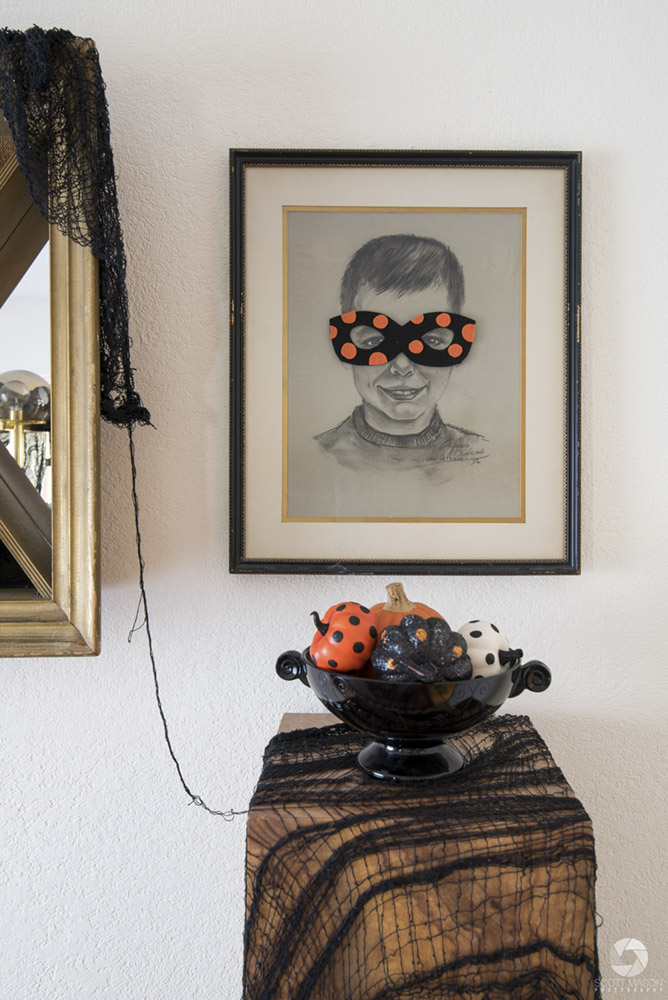 a one-point perspective photo of a wall with a child's portrait drawing and a decorative Halloween bowl