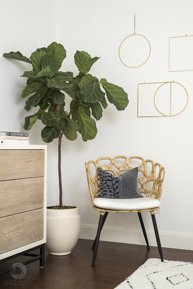 a vertical photo of an indoor potted plant next to a chair and part of a dresser