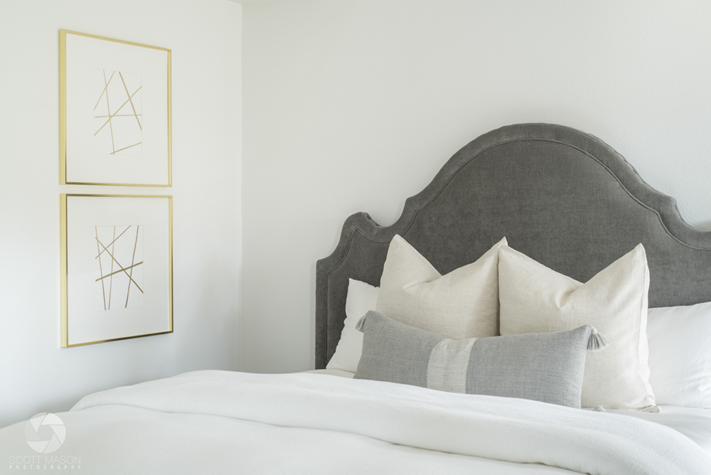 a cropped image of the corner of a room, with two picture frames over a bed