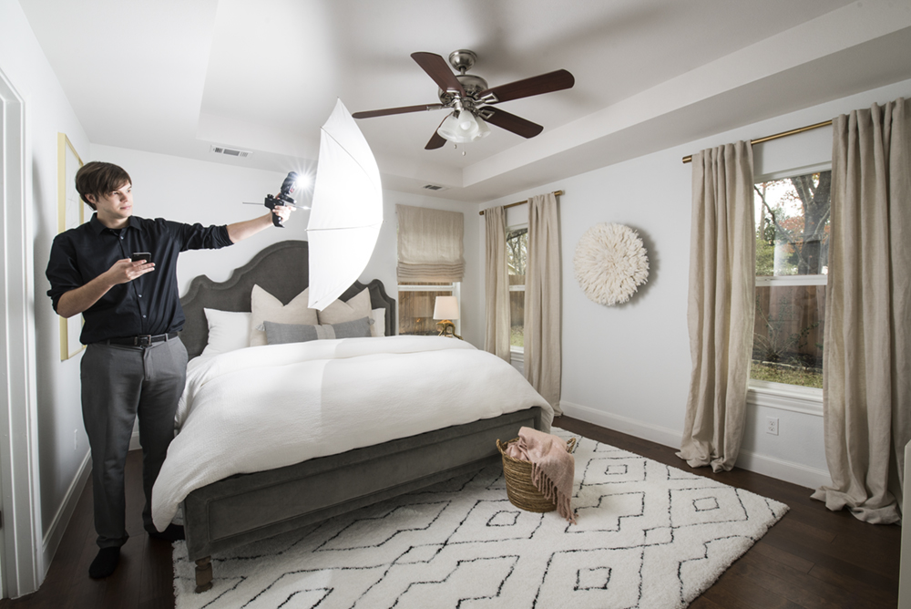 an image of a photographer hand-holding a flash umbrella in a bedroom