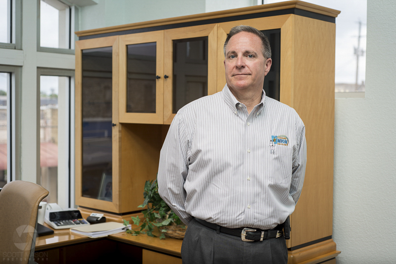 a horizontal portrait of an executive bank director standing in his office with his hands behind his back