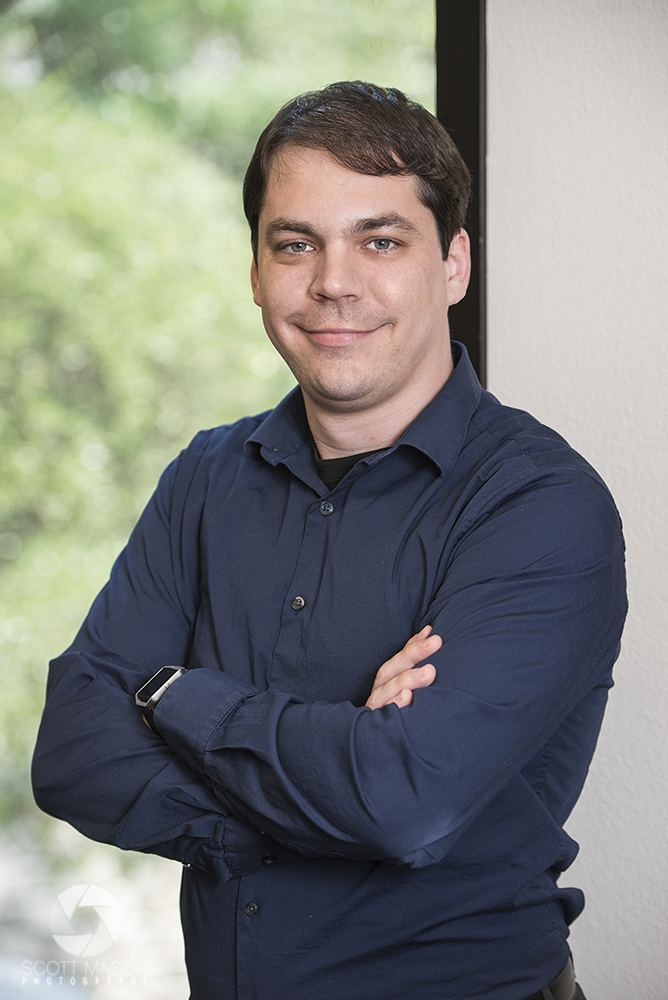 a man crossing his arms and smiling in an office