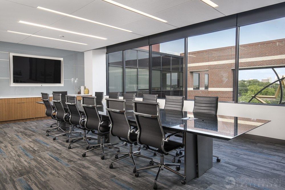 a photo of a conference room showing a long conference table, window and television screen