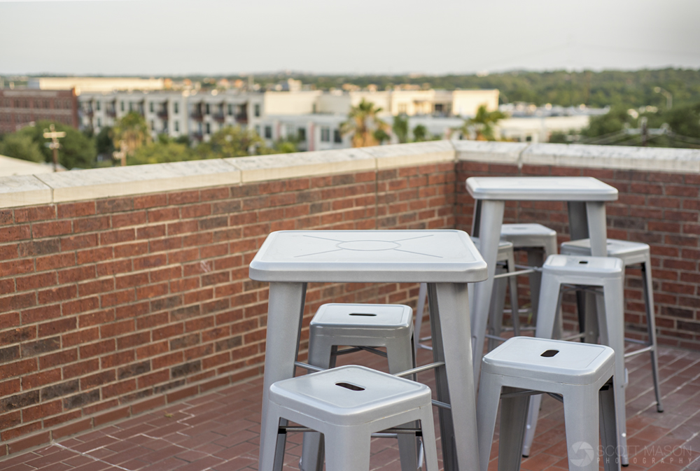 a close-up phot of chairs and tables on a brick patio at sunset