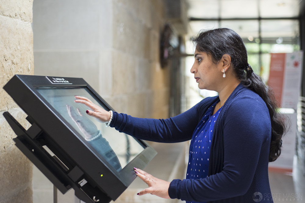 a woman at an electronic kiosk touching the display