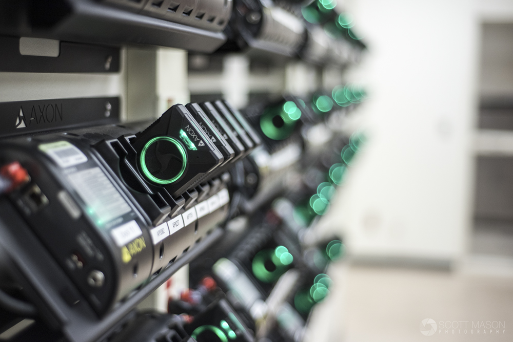 a photo looking down a row of body cam stations at a police department