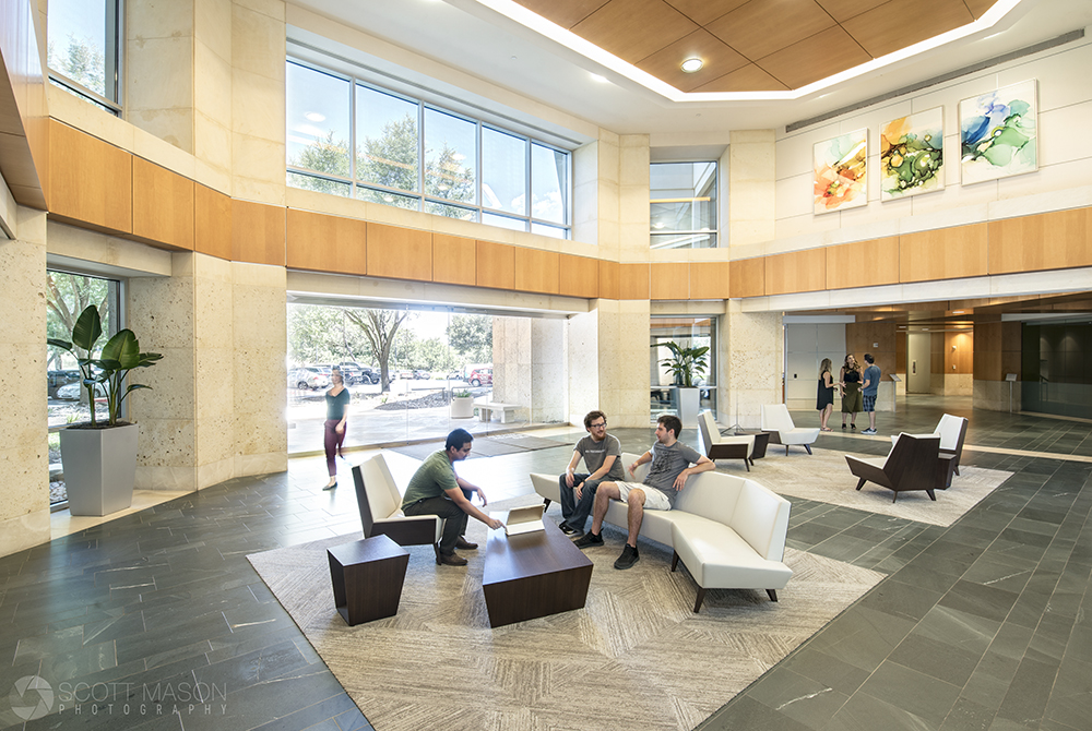 a wide view of an office lobby with people sitting around, and talking