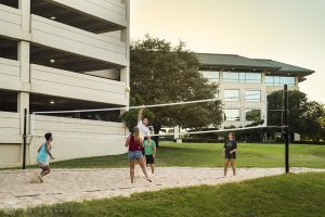 a lifestyle photo of people playing volleyball behind an office building at sunset