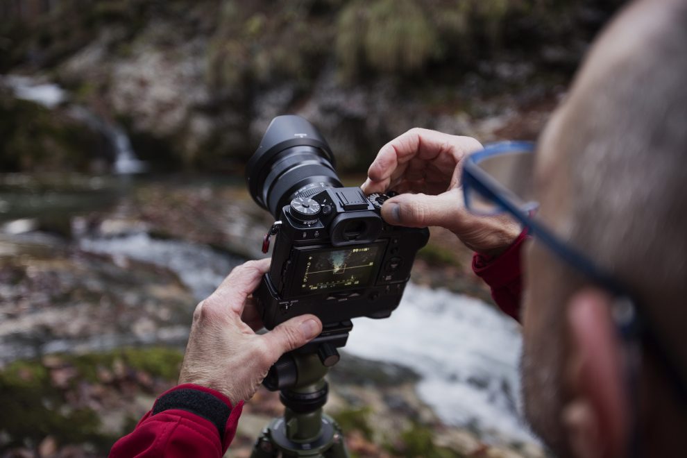 a man photographing a river with a mirrorless camera
