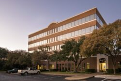 the front exterior of a three-story office building at sunset