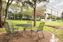 an office building with trees, a table and chairs in front