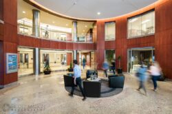 the lobby of an office building with workers walking through it