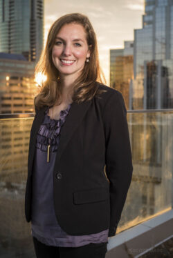 a business portrait/headshot of a smiling woman standing on a rooftop downtown